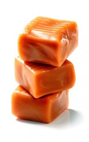 Three stacked orange caramel candies with glossy surface on white background