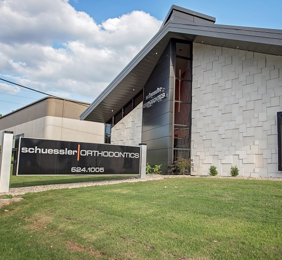 Schuessler Orthodontics modern brick building with front lawn sign and clear blue sky.