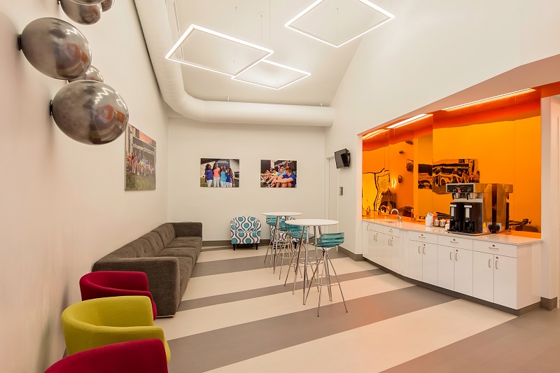 Modern orthodontic office waiting room with colorful seating, bright orange accent wall, and contemporary design elements.