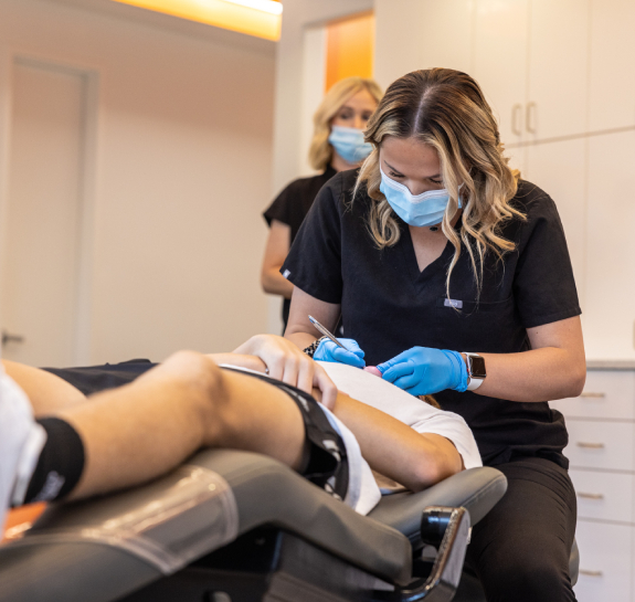 Orthodontist in blue gloves examines patient's teeth in modern dental office.