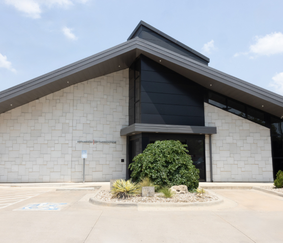 Modern orthodontic office building with brick facade, dark roof overhang, and landscaped entrance.